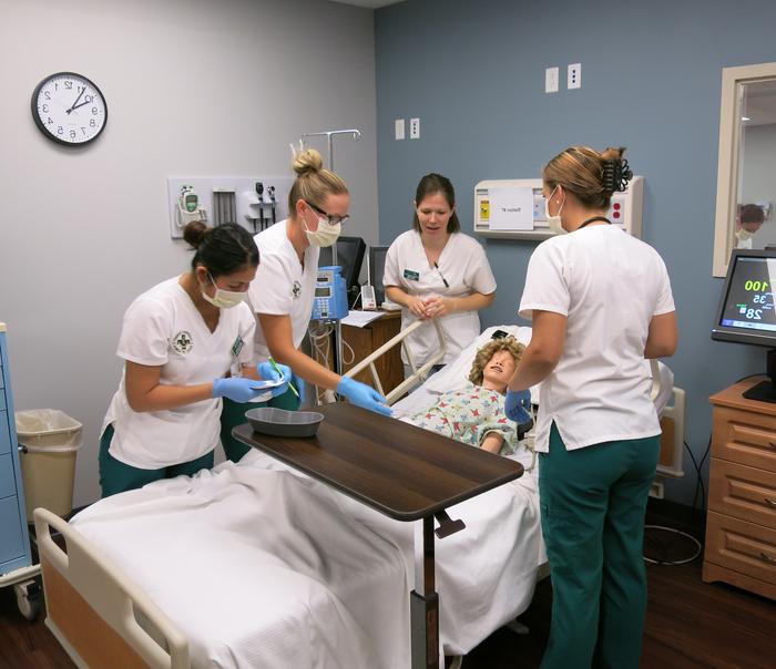 Nursing students performing a simulation on a medical maniken.