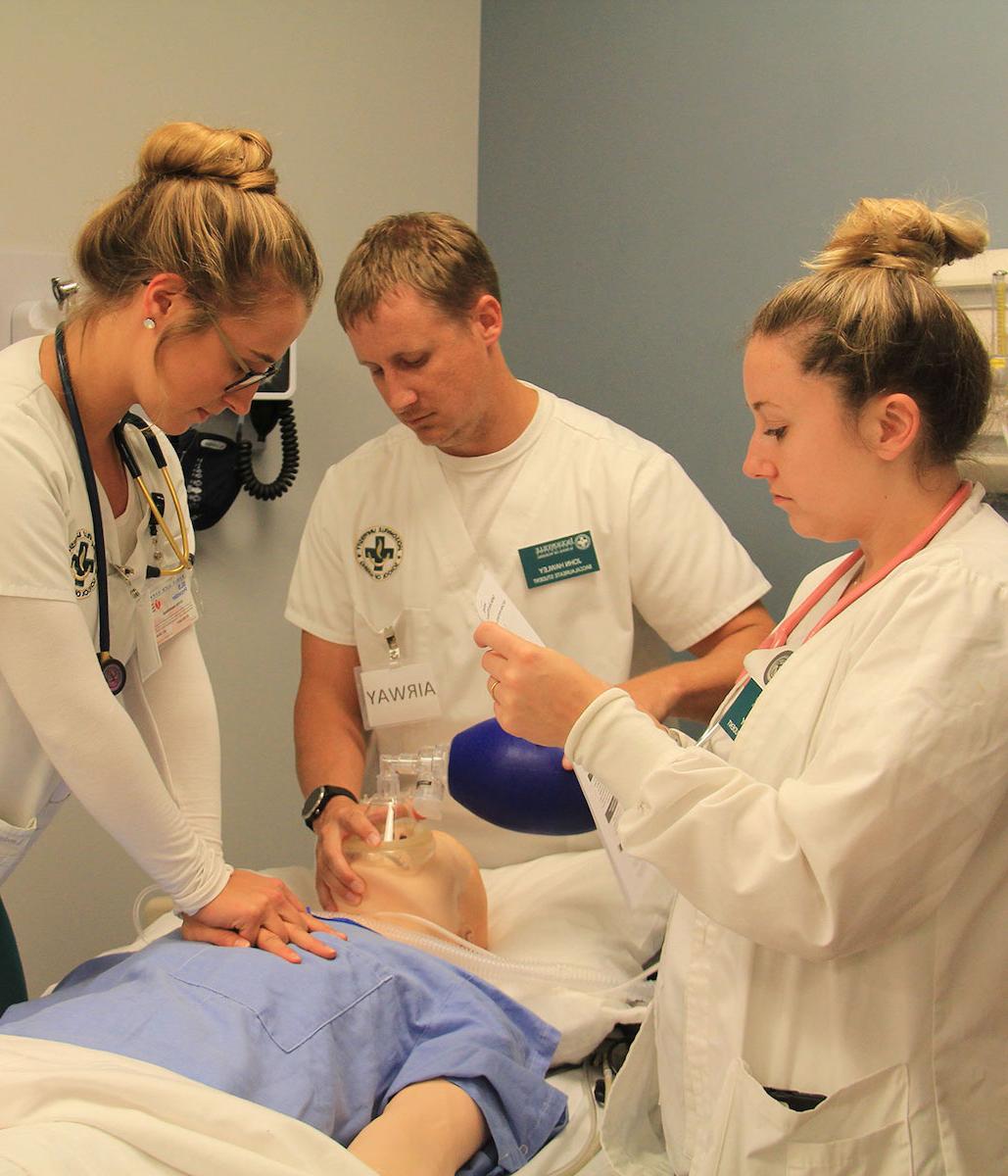 Three students practice on a mannequin in the Simulation Center.